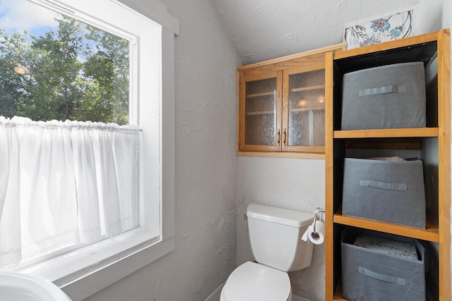 half bath featuring a textured wall and toilet