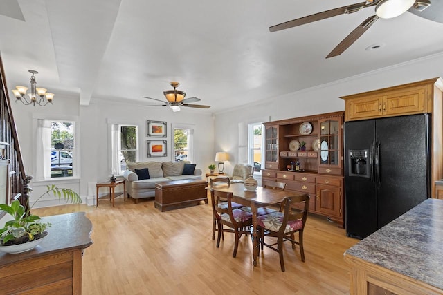 dining space with light wood-style flooring, ornamental molding, a wealth of natural light, and ceiling fan with notable chandelier