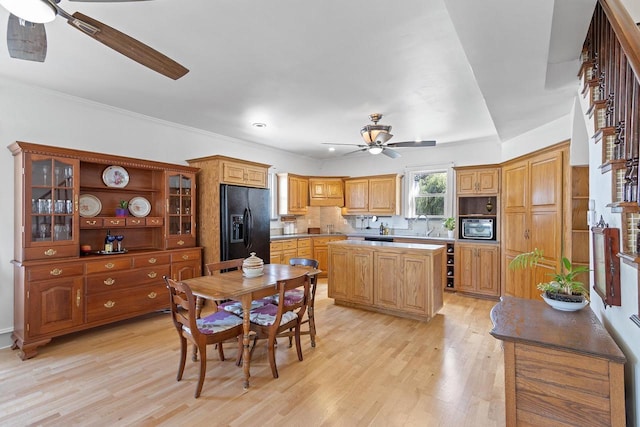 kitchen featuring light wood-style flooring, a kitchen island, a ceiling fan, decorative backsplash, and black refrigerator with ice dispenser