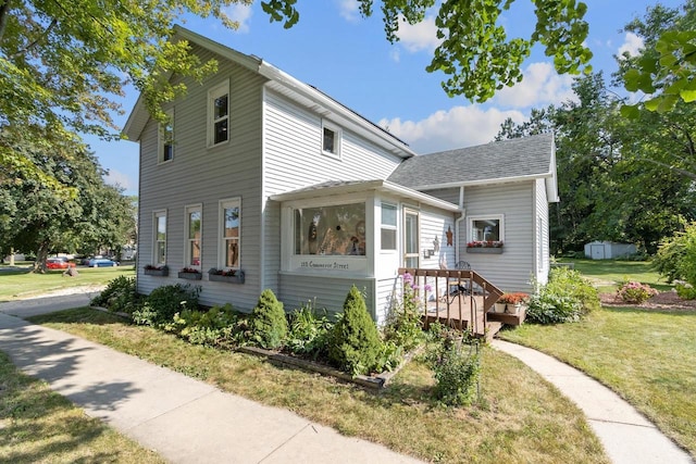 american foursquare style home featuring a shingled roof and a front yard