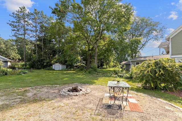 view of yard featuring a storage unit, an outdoor fire pit, a patio area, and an outbuilding