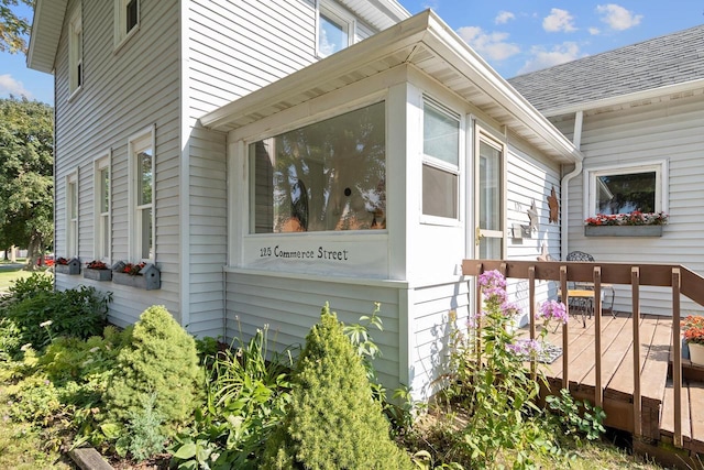 view of home's exterior with a shingled roof and a wooden deck