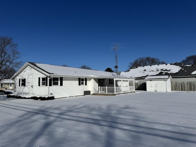 view of front of property featuring a porch, an outbuilding, fence, and a storage unit