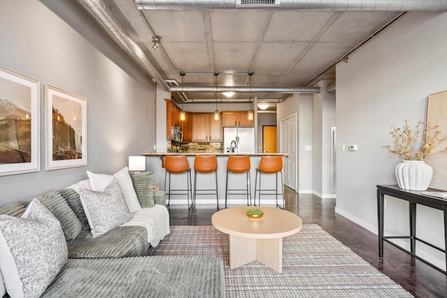 living room featuring finished concrete floors, visible vents, and baseboards