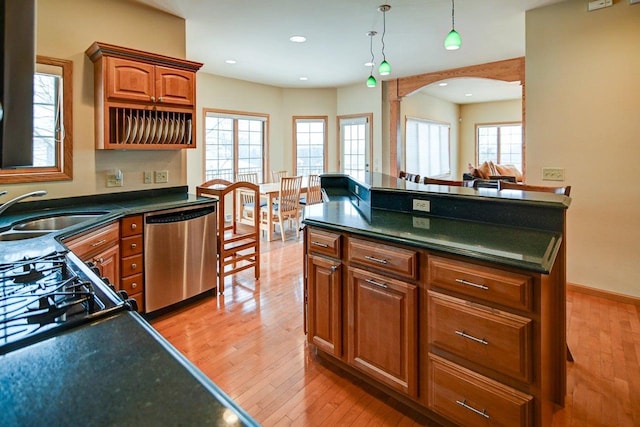 kitchen with dishwasher, dark countertops, brown cabinets, wood finished floors, and a sink