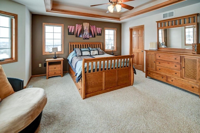 bedroom with visible vents, a tray ceiling, baseboards, and light colored carpet