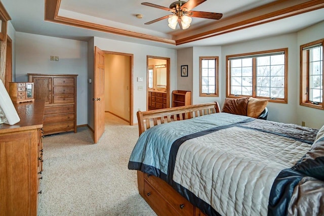 bedroom with a raised ceiling, multiple windows, light carpet, and baseboards