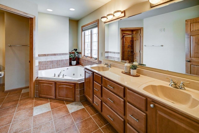 bathroom featuring tile patterned flooring, a sink, a tub with jets, and double vanity