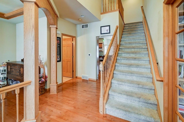 stairs featuring a towering ceiling, wood finished floors, visible vents, and baseboards