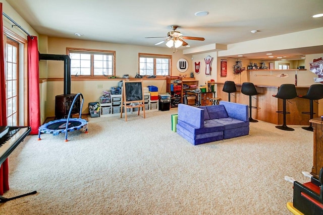 recreation room featuring a bar, ceiling fan, and carpet floors