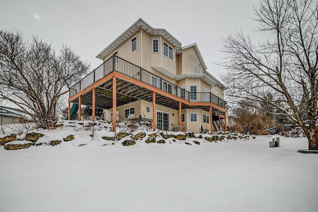 snow covered rear of property featuring a deck