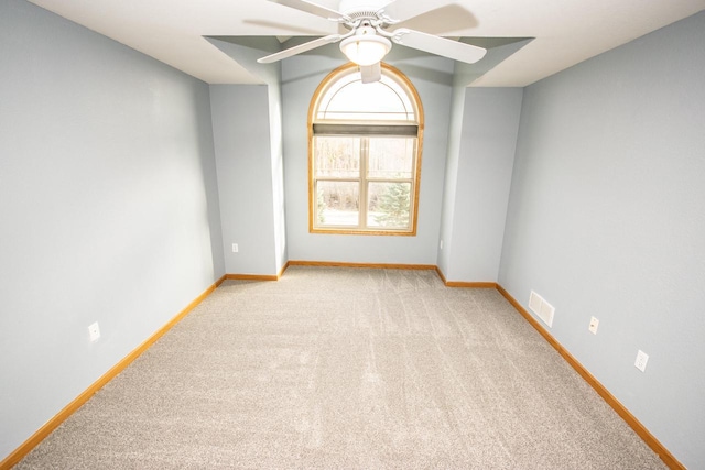 empty room with baseboards, visible vents, a ceiling fan, and light colored carpet