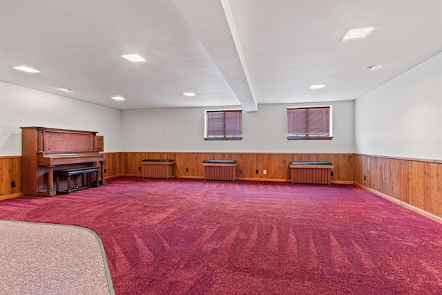 misc room featuring carpet, radiator heating unit, wood walls, and wainscoting