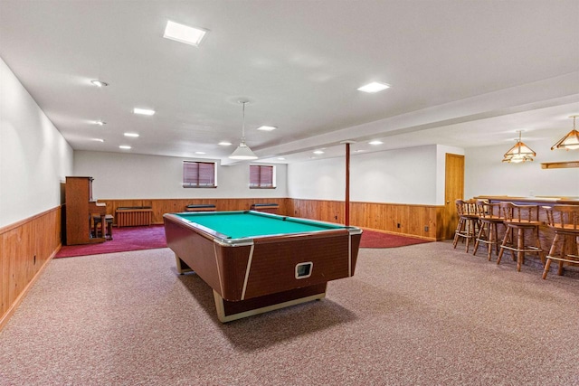 recreation room with a bar, a wainscoted wall, wooden walls, and carpet flooring