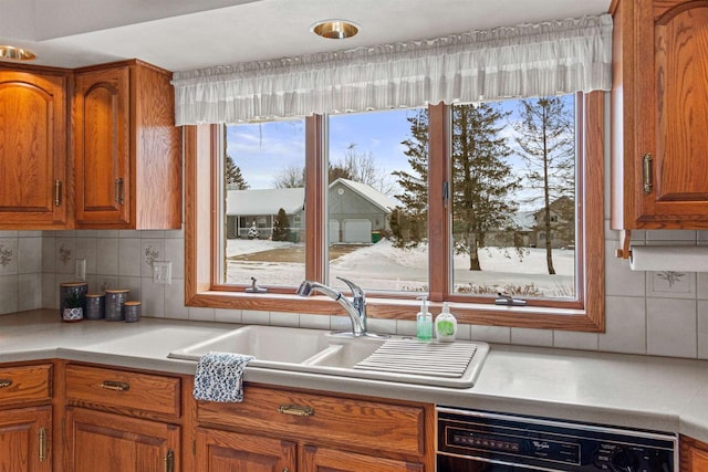 kitchen featuring dishwasher, light countertops, a sink, and brown cabinets