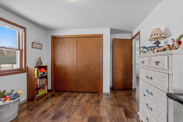 bedroom with baseboards, dark wood finished floors, and a closet