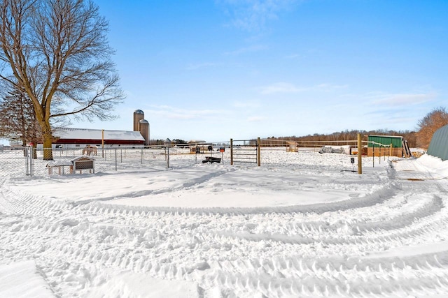 yard covered in snow with a rural view and fence