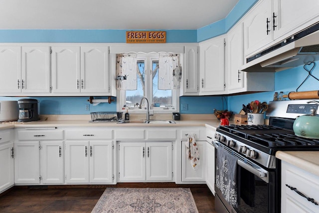 kitchen with stainless steel gas range oven, white cabinets, light countertops, under cabinet range hood, and a sink