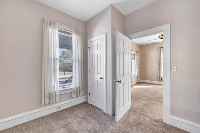 hallway featuring light carpet, plenty of natural light, and baseboards