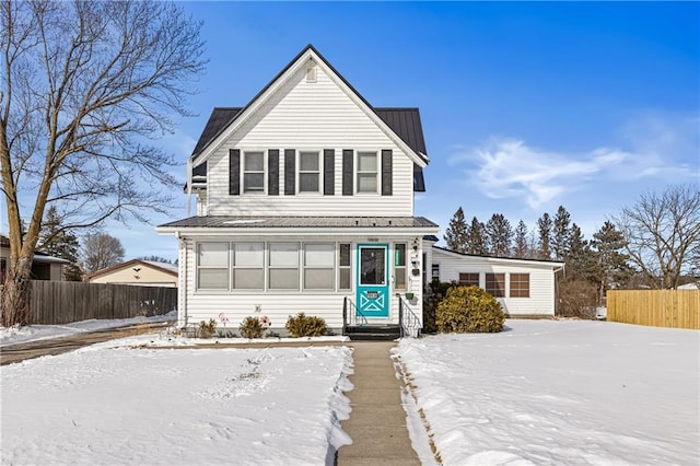 traditional-style home with entry steps, metal roof, and fence