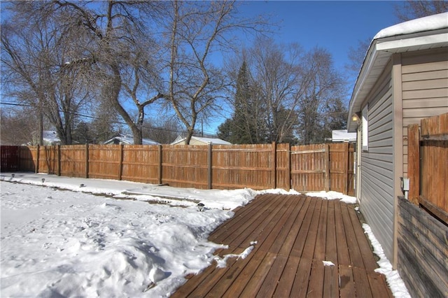 snow covered deck featuring a fenced backyard