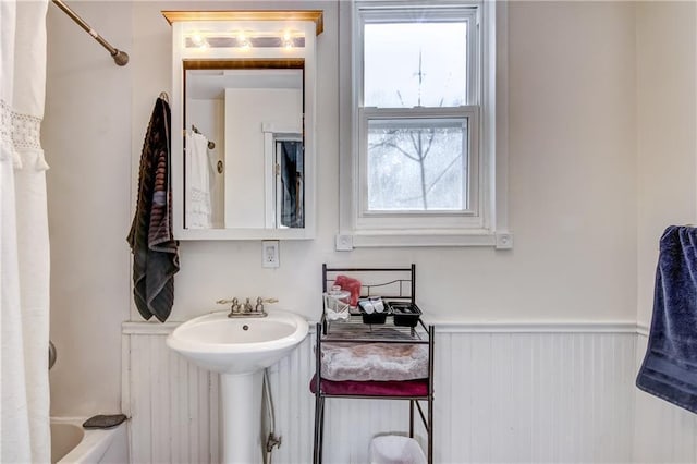 bathroom featuring shower / bath combo, wainscoting, and a sink