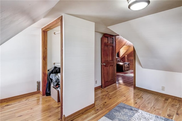 bonus room with light wood-style floors, baseboards, and vaulted ceiling