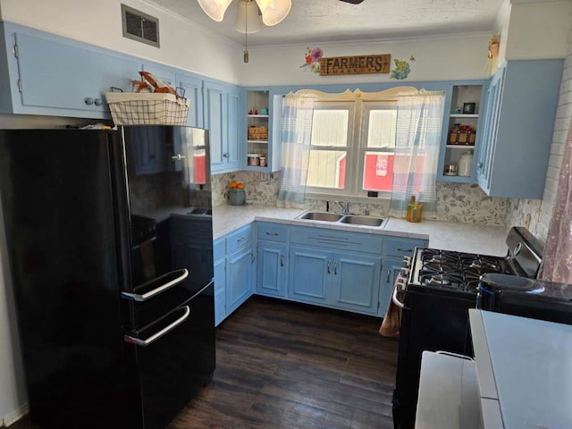 kitchen featuring range with gas stovetop, freestanding refrigerator, light countertops, open shelves, and a sink