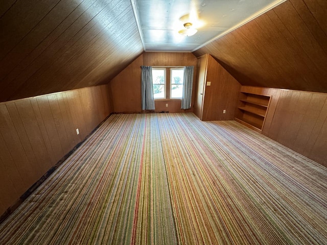 additional living space featuring lofted ceiling, built in shelves, wooden walls, wood ceiling, and carpet