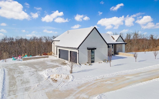 snow covered property with an outdoor structure, a forest view, and a detached garage