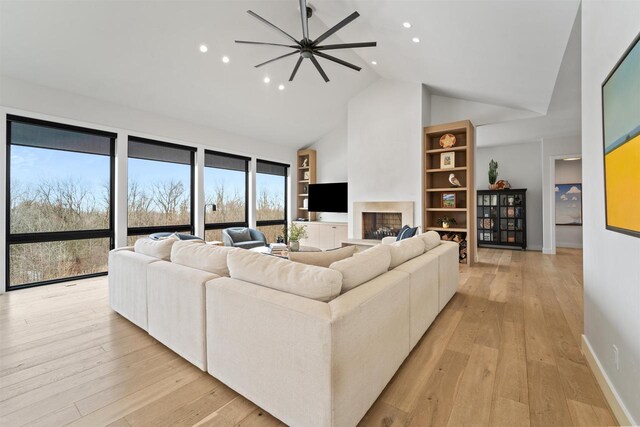 W4038 Maplewood Ln, Fond Du Lac, WI 54937 - living room featuring built in features, baseboards, light wood finished floors, high vaulted ceiling, and a fireplace with raised hearth