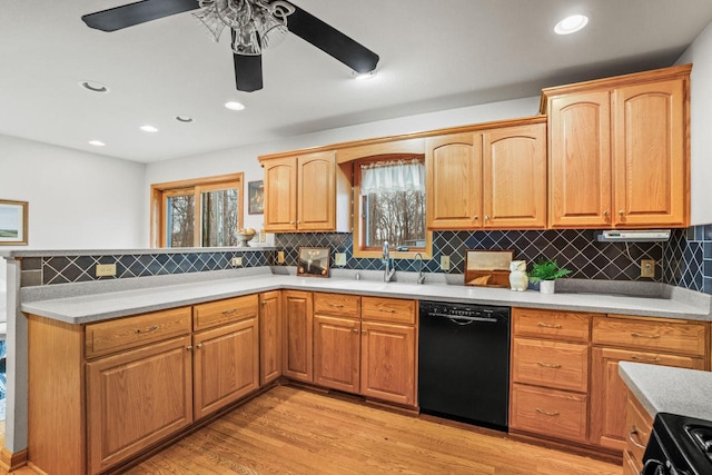 kitchen with a sink, a peninsula, black appliances, and light wood finished floors