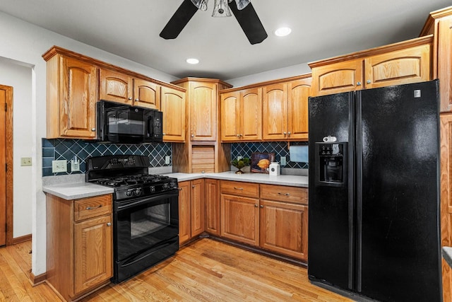 kitchen featuring tasteful backsplash, light countertops, light wood finished floors, and black appliances