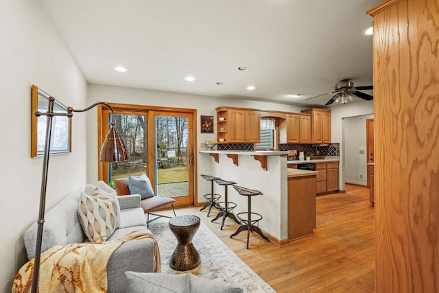 kitchen with tasteful backsplash, a breakfast bar, a peninsula, light wood-type flooring, and open shelves