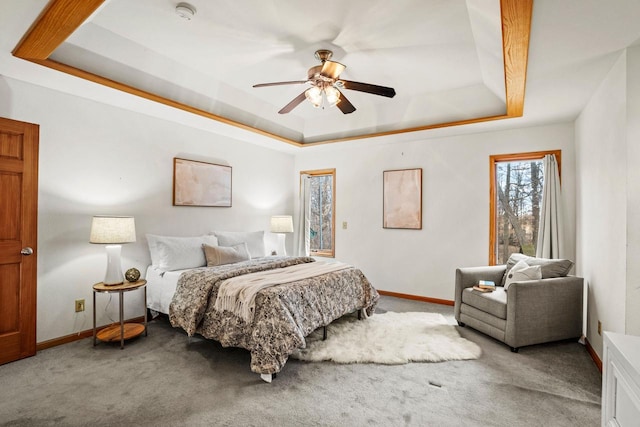 carpeted bedroom featuring baseboards, a raised ceiling, and a ceiling fan