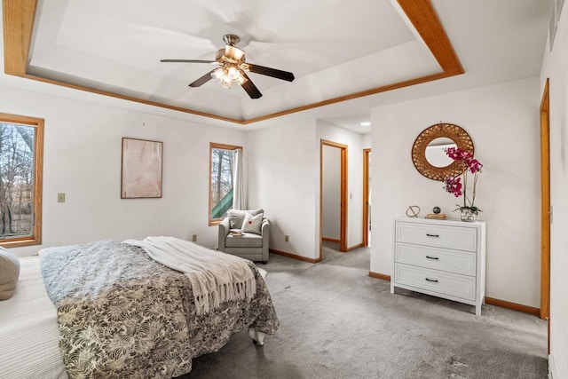 carpeted bedroom featuring a tray ceiling, a ceiling fan, and baseboards