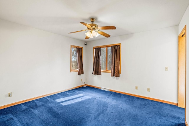 empty room with ceiling fan, carpet flooring, visible vents, and baseboards