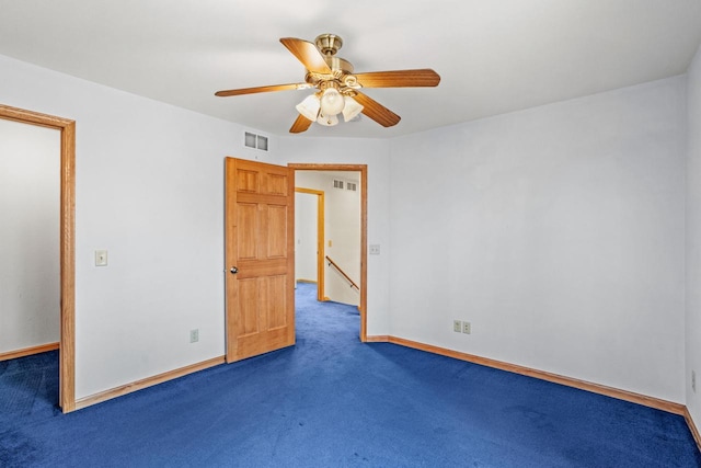 carpeted spare room with baseboards, visible vents, and ceiling fan