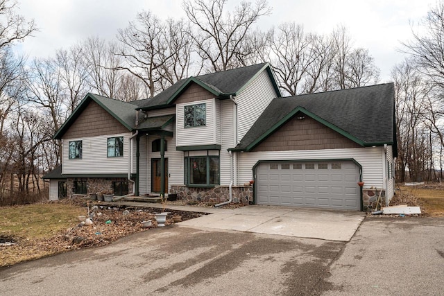 view of front of house with driveway, stone siding, an attached garage, and a shingled roof