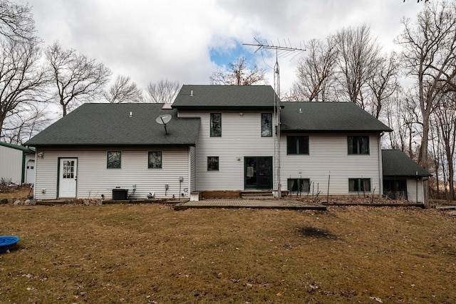 back of house with roof with shingles and a yard