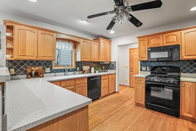 kitchen featuring light wood-type flooring, black appliances, light countertops, and a sink