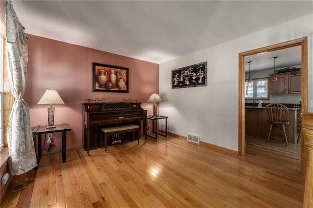 sitting room featuring visible vents, light wood-style flooring, and baseboards