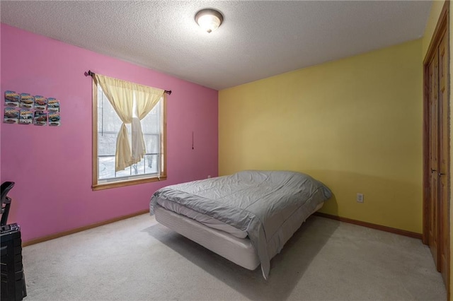 bedroom featuring light colored carpet, a textured ceiling, and baseboards