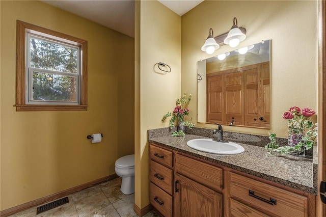 bathroom featuring toilet, vanity, visible vents, baseboards, and a closet