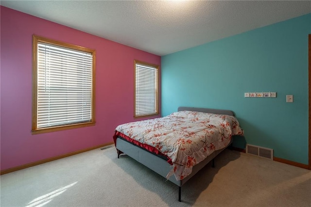 bedroom featuring baseboards, visible vents, a textured ceiling, and light colored carpet