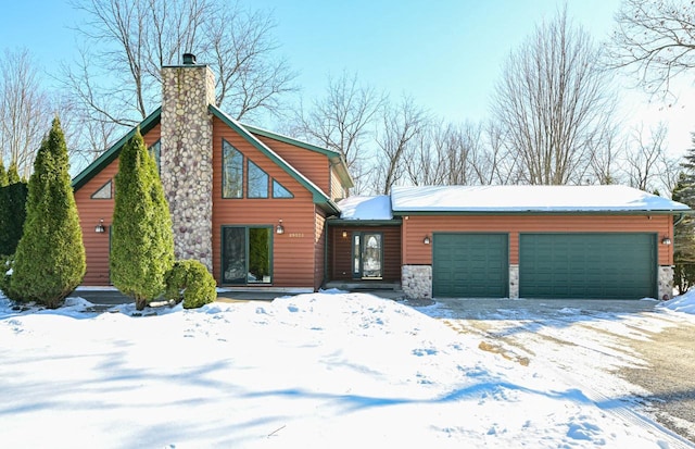 view of front of house with an attached garage, stone siding, and a chimney