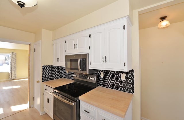 kitchen with white cabinets, tasteful backsplash, stainless steel appliances, and light countertops