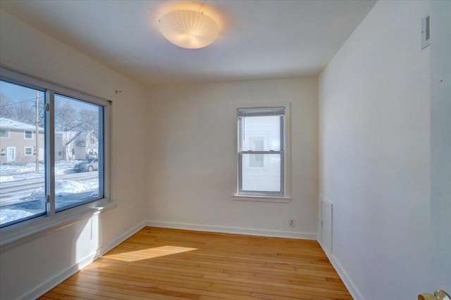 spare room with a healthy amount of sunlight, light wood finished floors, and baseboards