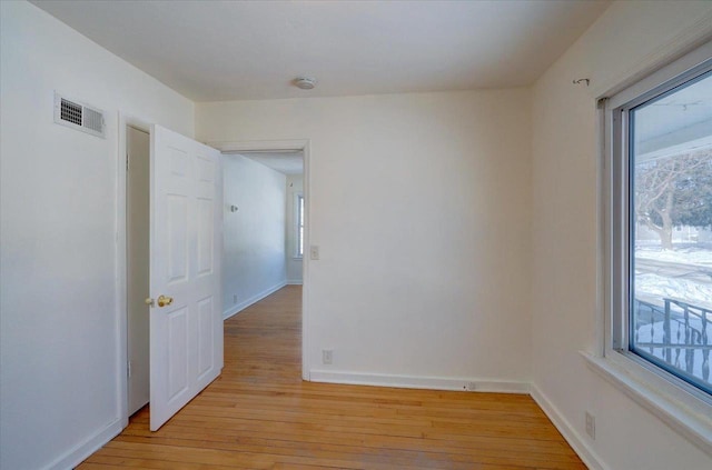 spare room featuring baseboards, visible vents, and light wood-style floors