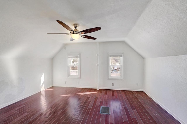 bonus room with a textured ceiling, dark wood finished floors, visible vents, and lofted ceiling